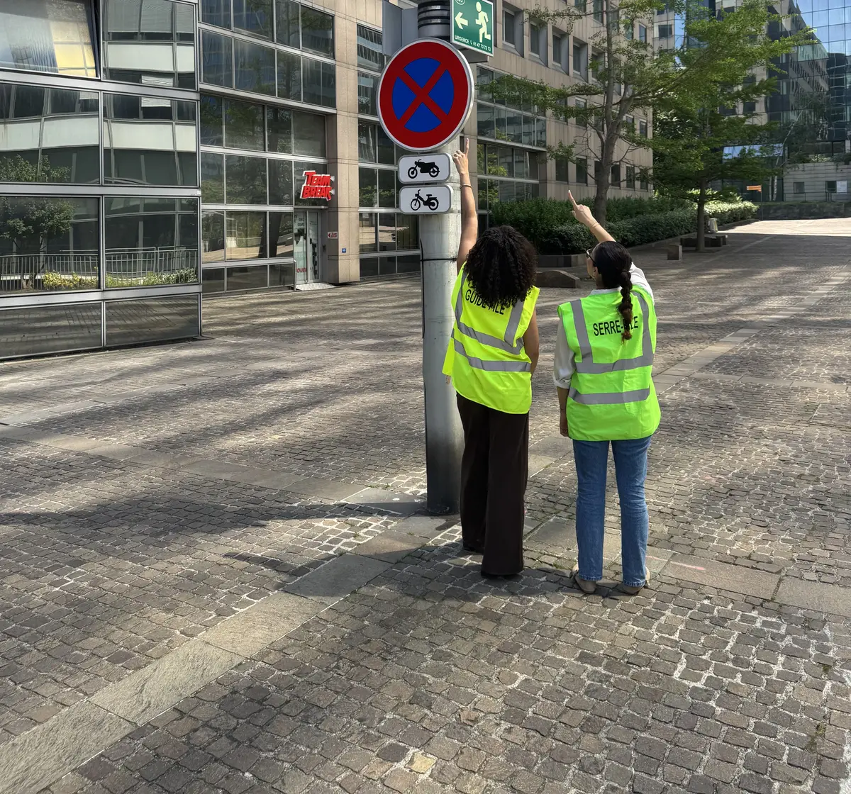 Deux participantes en gilet repèrent le point de rassemblement lors d'un exercice d'évacuation